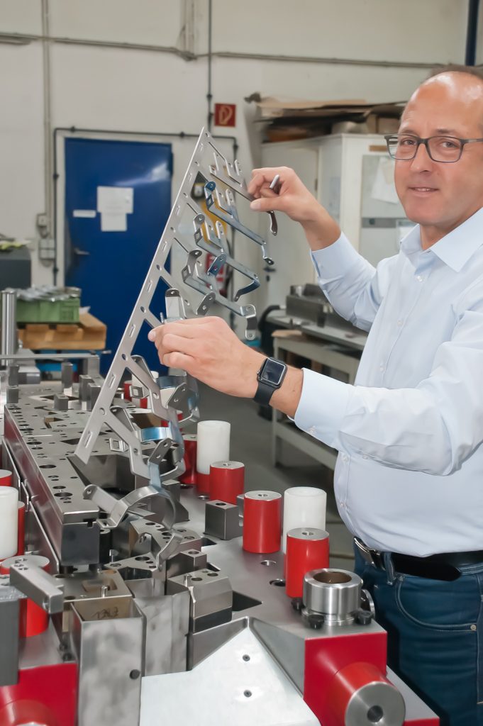 Eine Hälfte des fertig montierten Folgeverbundwerkzeugs für einen Halter: Firmenchef Frank Ebel hält den dazugehörenden Teststreifen in der Hand.